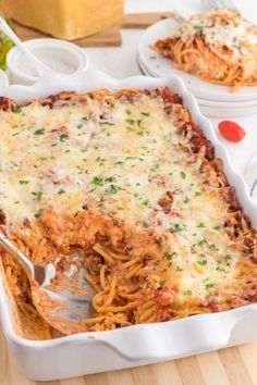 a casserole dish with meat and cheese in it on a wooden table next to other dishes