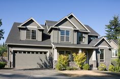 a large gray house with two garages and three windows on the front of it