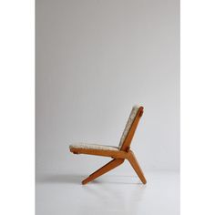 a wooden chair sitting on top of a white floor next to a wall with a light colored background