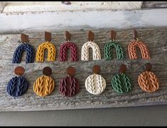 several different colored leather earrings hanging on a piece of wood