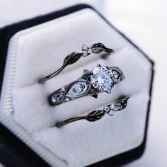 three engagement rings sitting on top of a white box with black and silver trimmings