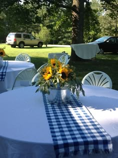 the table is set with sunflowers and blue gingham cloth