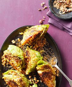 some food is on a plate with a fork and spoon next to it, including brussel sprouts