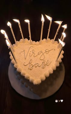 a heart shaped cake with lit candles in the shape of a love sign on it