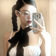 a woman wearing glasses and a black tie holding up a cell phone to take a selfie