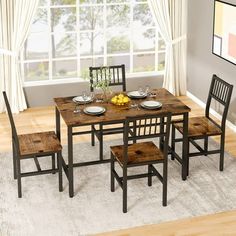 a dining room table with four chairs and a bowl of fruit on the table next to it