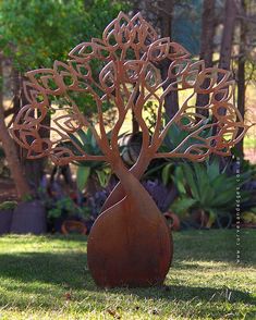 a metal tree sculpture sitting on top of a lush green field