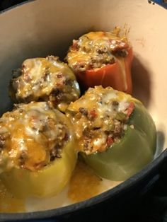 three stuffed peppers in a pan with cheese on top