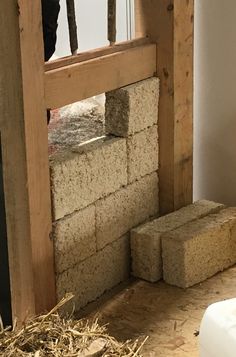 the interior of a house being built with bricks and straw on the floor next to it