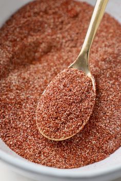 a spoon full of ground spices in a white bowl with a gold spoon sticking out of it