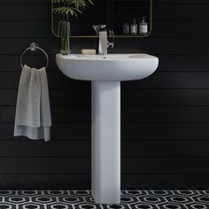 a white sink sitting under a mirror next to a towel rack and potted plant