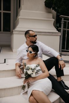 a man sitting next to a woman on top of a set of stairs wearing sunglasses