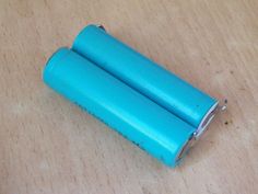 two blue batteries sitting on top of a wooden table