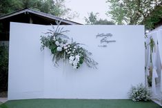 a white wall with flowers and greenery on it