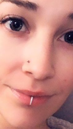 a close up of a person with piercings on her nose