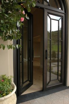 an open door to a house with potted plants