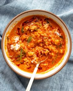 a bowl filled with meat and vegetables on top of a blue cloth next to a spoon