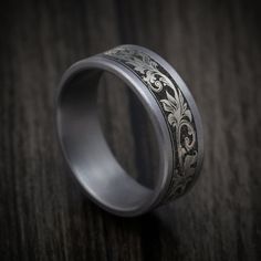 a wedding ring with an intricate design on the inside and outside, sitting on a wooden surface