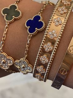 four different bracelets on a woman's arm with gold and blue charms in the middle