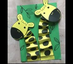 two giraffes made out of paper on top of a green sheet of paper