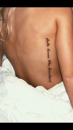 a woman laying in bed with her back turned to the camera and has a tattoo that reads, i love you forever