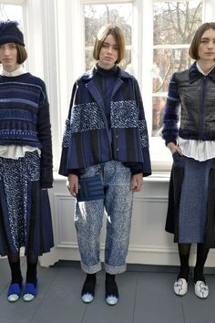 three models standing next to each other in front of a window wearing blue and black clothing