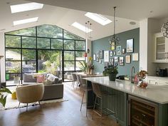 an open kitchen and living room area with skylights above the dining table, couches and chairs