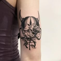 a woman with a bull's head and flowers on her arm is wearing a tattoo