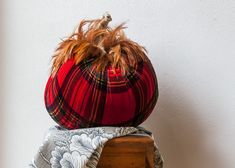 a red and black plaid hat sitting on top of a wooden box next to a white wall