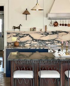 a kitchen with marble counter tops and stools in front of an open oven hood