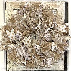 a wreath made out of burlocks and paper stars on a white door frame