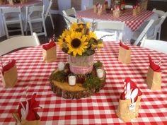 a table with red and white checkered tables cloths, sunflower centerpiece