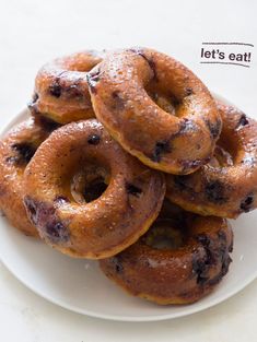 blueberry donuts stacked on top of each other on a white plate with the words let's eat written above them