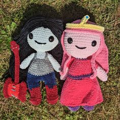 two crocheted dolls are laying on the grass with one wearing a crown and holding a shovel