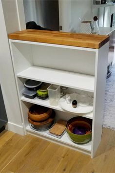 a white shelf with bowls and plates on it