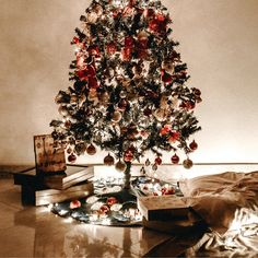 a small christmas tree with ornaments on it in front of a pile of books and other items