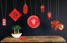 a wooden table topped with lots of red paper lanterns hanging from it's sides