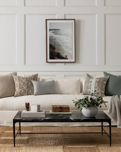 a living room filled with furniture and a painting hanging on the wall above it's coffee table