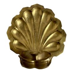 a brass shell shaped candle holder on a white background