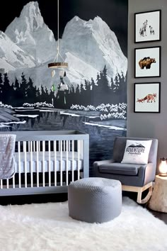 a baby's room decorated in gray and white with mountains painted on the wall