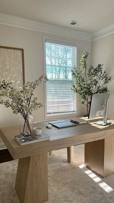 a wooden table with vases and flowers on it in front of a large window