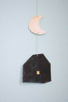 a small wooden house with a moon hanging from it's side on a string