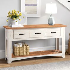 a white table with two drawers under a stair case next to a bag and flowers