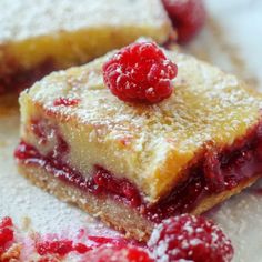 raspberry cheesecake bars with powdered sugar and fresh berries on the top