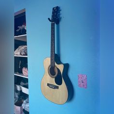 an acoustic guitar hanging on the wall next to a closet full of clothes and shoes