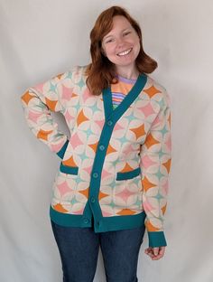 This item is slim-fit. Please use our sizing guide and order one size larger if you are unsure. Kiss your 2.5 children goodbye and dedicate your life to the future of technology! Inspired by the 1950s atomic movement, this unique and eye-catching cardigan features a custom atomic pattern in bold, vibrant colors. Long sleeve 100% cotton cardigan Slim-fit sizing Custom atomic patterning Blue/green collar Custom "Sleepy Peach" tag on collar Pockets Eric is 5'6" and wearing the medium size. Juliet i Future Of Technology, Futuristic Style, Collared Greens, Cardigan Sweater Jacket, Retro Futuristic, Cotton Cardigan, Retro Futurism, To The Future, The 1950s