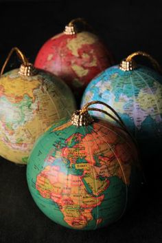 four globe ornaments are sitting on a black surface