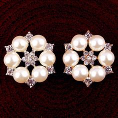 two pairs of pearl and crystal earrings on a red velvet surface, one is white