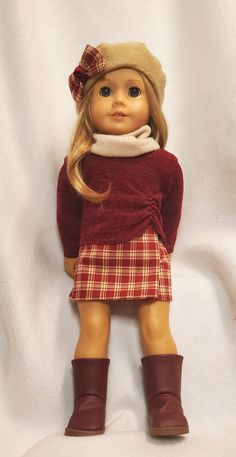 the doll is wearing a red sweater and plaid skirt with brown boots on her feet