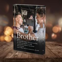 a book with two men holding hands on top of a wooden table and blurry lights in the background